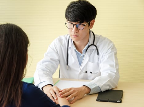 Young asian doctor hands holding female patient hand for encouragement and empathy in office photo