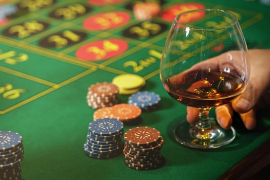 Man playing roulette in casino. Close up of male hands with a glass of cognac and chips. photo