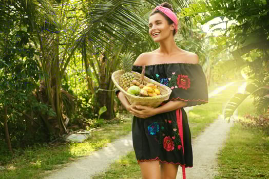 Happy young woman with a basket full of exotic fruits photo