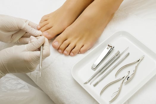 Pedicure master work. Close up of female nails and pedicurist hands in gloves with special tools. photo