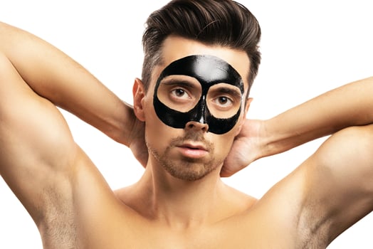 Young guy with a black charcoal mask on his face on white background. photo