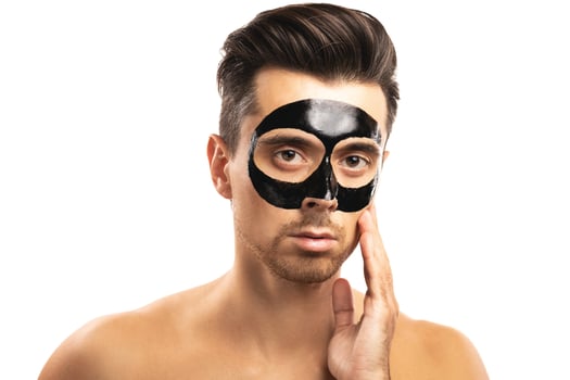 Young guy with a black charcoal mask on his face on white background. photo