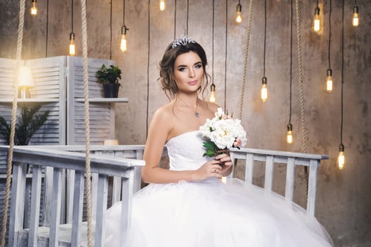 Young happy bride wearing beautiful lush dress in the room with a lot of light bulbs photo