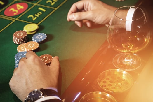 Man playing roulette in casino. Close up of male hands with a glass of cognac and chips. photo