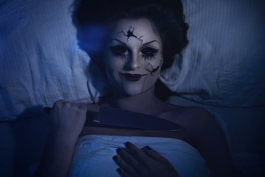 Spooky porcelain speaking doll holding knife and lying in the bed photo