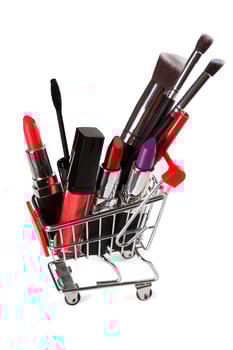 Different makeup objects in shopping cart on white photo