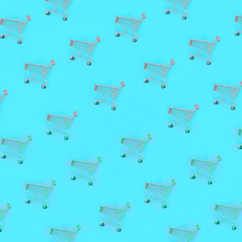 Shopping addiction, shopping lover or shopaholic concept. Many small empty shopping carts perform a pattern on a pastel colored paper background. Flat lay composition, top view photo