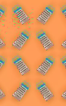 Small stainless steel graters lies on a pastel colored paper. Kitchen accessories. Tools for cooking. Flat lay top view photo
