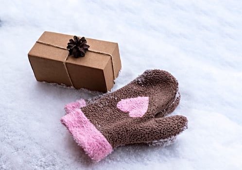 Gift in craft box decorated with pine cone on white snow and mittens with pink heart, eco friendly eco concept Merry Christmas and New Year photo