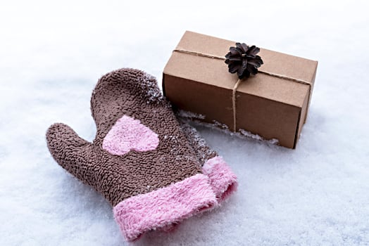 Gift in craft box decorated with pine cone on white snow and mittens with pink heart, eco friendly eco concept Merry Christmas and New Year photo