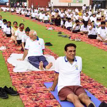 New Delhi, India, June 21 2022 - Group Yoga exercise session for people at Yamuna Sports Complex in Delhi on International Yoga Day, Big group of adults attending yoga class in cricket stadium photo