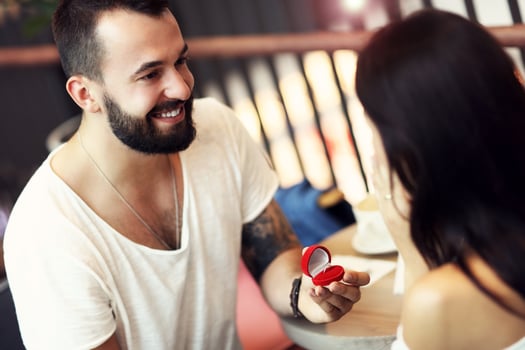 Handsome man proposing to beautiful woman in cafe photo