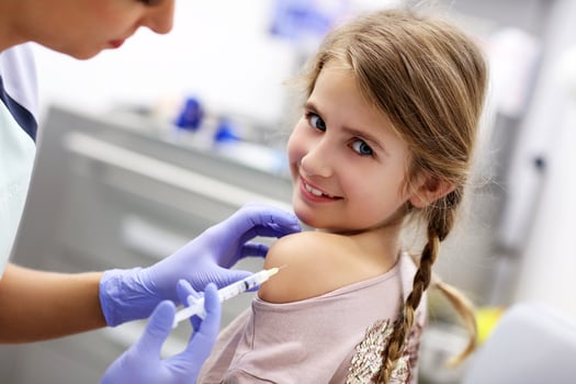Brave little girl receiving injection or vaccine with a smile photo