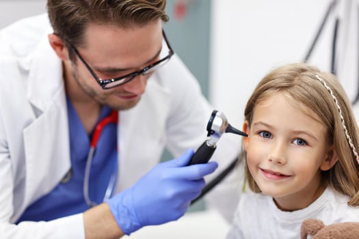Close-up Of Male Doctor Examining Girl's Ear With An Otoscope photo