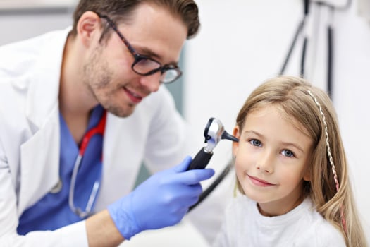 Close-up Of Male Doctor Examining Girl's Ear With An Otoscope photo