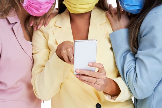 Three women in pastel suits posing with smartphones over white background photo
