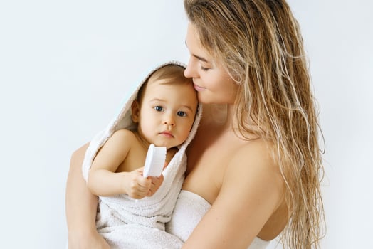 Young and happy mother and her cute little baby after bathing photo
