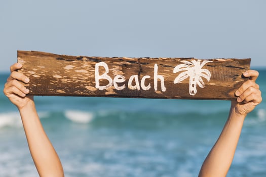 Female hand and old wooden sign with lettering Beach photo