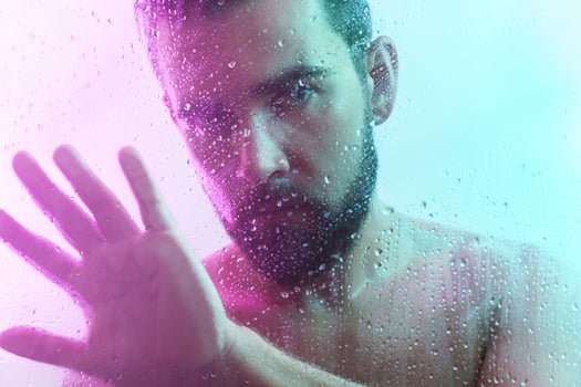Portrait of handsome man through wet glass in neon light photo