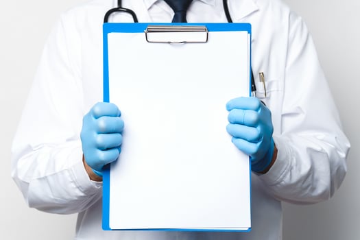 Doctor is holding a clipboard with a blank white paper photo