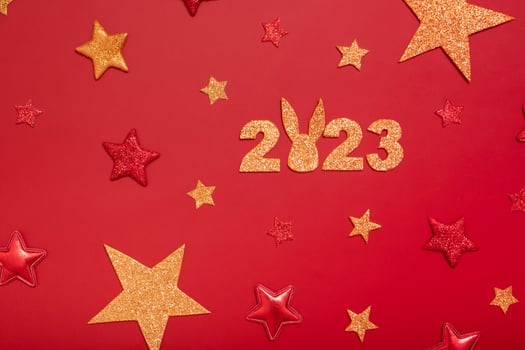 2023 new year flat lay concept. Numbers 2023 with red and gold stars and rabbit, top view on red background photo