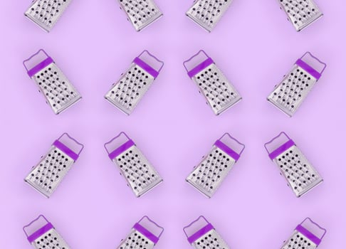 Small stainless steel graters lies on a pastel colored paper. Kitchen accessories. Tools for cooking. Flat lay top view photo