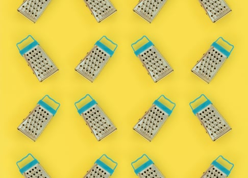 Small stainless steel graters lies on a pastel colored paper. Kitchen accessories. Tools for cooking. Flat lay top view photo