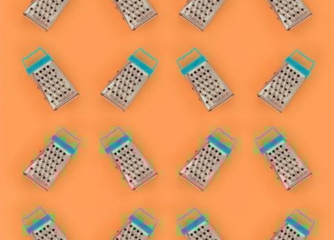 Small stainless steel graters lies on a pastel colored paper. Kitchen accessories. Tools for cooking. Flat lay top view photo