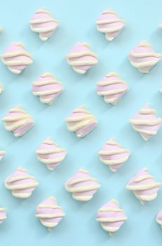 Colorful marshmallow laid out on blue paper background. pastel creative textured pattern. minimal photo