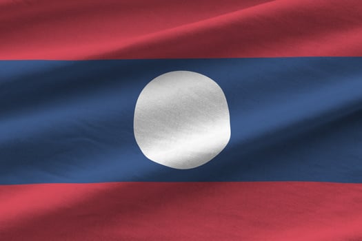 Laos flag with big folds waving close up under the studio light indoors. The official symbols and colors in banner photo