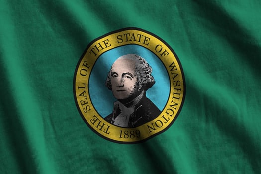 Washington US state flag with big folds waving close up under the studio light indoors. The official symbols and colors in banner photo