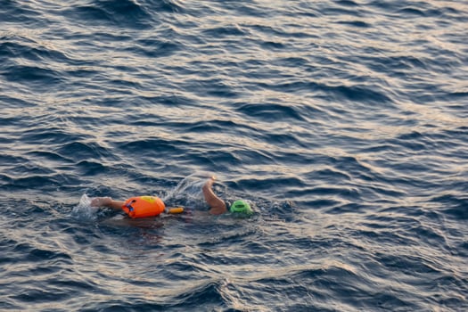 Swimmer swimming in open water in the Mediterranean Sea with a safety buoy photo
