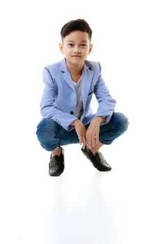 A 10-year-old Asian boy in a casual jacket is sitting smart and happy looking at the camera against a white isolate background. photo