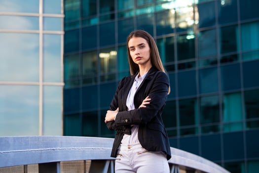 business woman with crossed arms. confident modern business woman standing near a large windows neer her office. photo