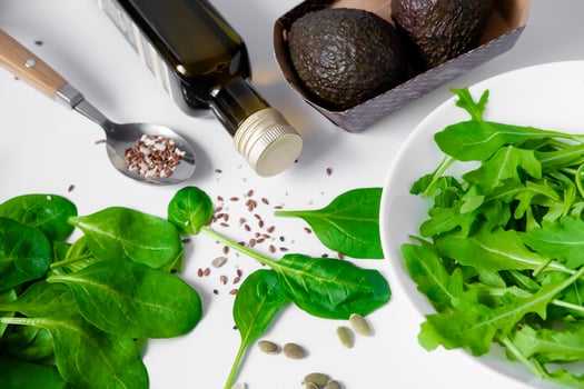 olive oil, avocado, spinach, arugula and sesame seeds on a white plate. Still life of healthy food. Composition of products for avocado salad. photo