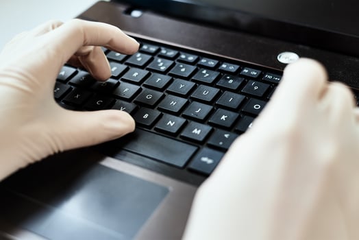 Hands in gloves typing on the laptop keyboard. Virus protection concept photo