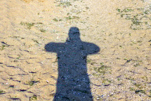 Shadow of man traveler with backpack take photo on sand beach at sunset time, Travel