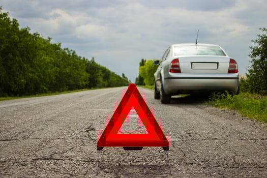 Red triangle of a car on the road. Car warning triangle on the road against the city in the evening. Breakdown of the car in bad weather. photo