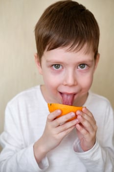 handsome boy licks an orange photo