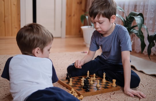 children play chess at home sitting on the floor photo