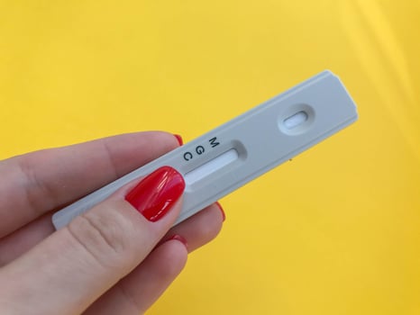medical procedures. coronavirus test on a bright yellow background. girl with bright red manicure holds a strip. IgG and IgM antibodies test photo