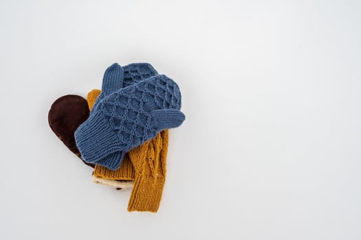 Several pairs of knitted, warm mittens lie in a pile on white, clean snow, on a cloudy winter day. Copy space. photo
