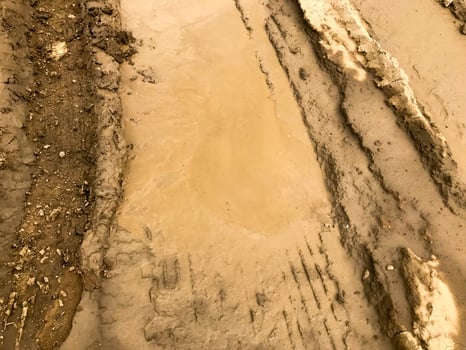 Texture of a dirty bad dirt road dirt road with puddles and clay drying mud with cracks and ruts. Off-road. The background photo