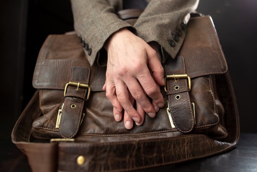 Teachers hands are on an old leather briefcase with metal buckles on the table. photo