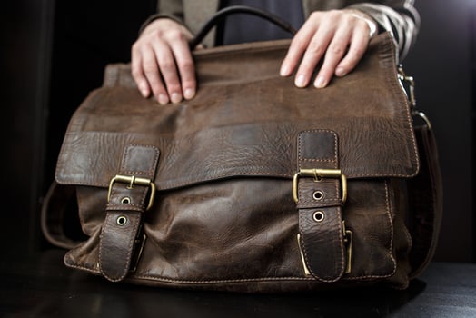 Teachers female hands hold on to an antique brown leather briefcase. photo