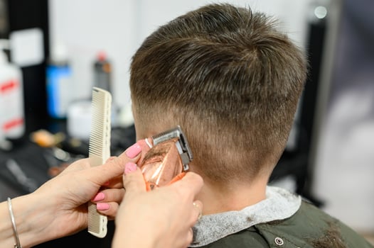 A teenager in a beauty salon gets a haircut, a hairdresser cuts a teenage boy's hair. photo