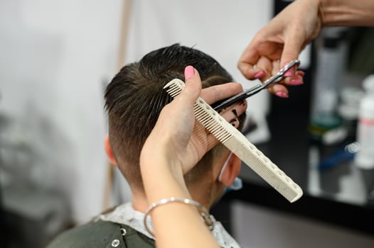 A teenager in a beauty salon gets a haircut, a hairdresser cuts a teenage boy's hair. photo
