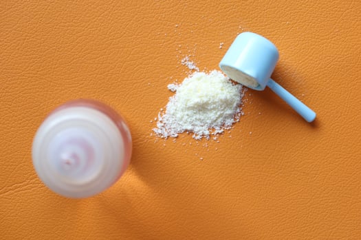 Close up of baby milk powder and spoon orange background photo