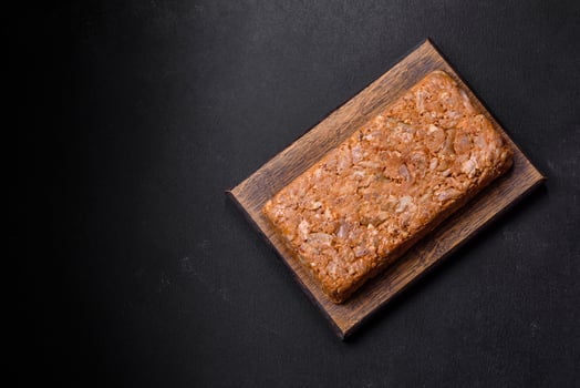Tasty meat brawn or roll on a wooden cutting board with spices and herbs photo