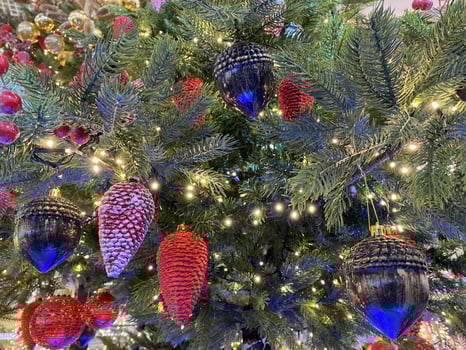 Christmas toys, balls of pink color, a shining garland hanging on the branch of the Xmas tree. Close-up photo